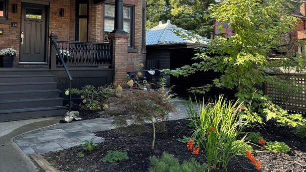 A two-story house with a front porch, a garage, and a well-maintained garden with various plants and flowers.