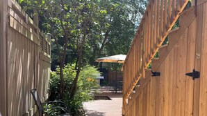 A wooden deck with a metal chair, a wooden fence, and a covered patio area.