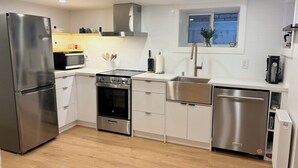 A modern kitchen with stainless steel appliances, white cabinets, and a window above the sink.