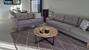 Una sala de estar moderna con dos sofás grises, una mesa de centro y un comedor con sillas y una mesa.