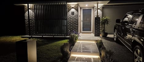 A modern house with a brick exterior, a gated entrance, and a driveway leading to a garage.