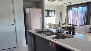 Una cocina moderna con una isla central, electrodomésticos de acero inoxidable, iluminación colgante y vistas al área de estar.
