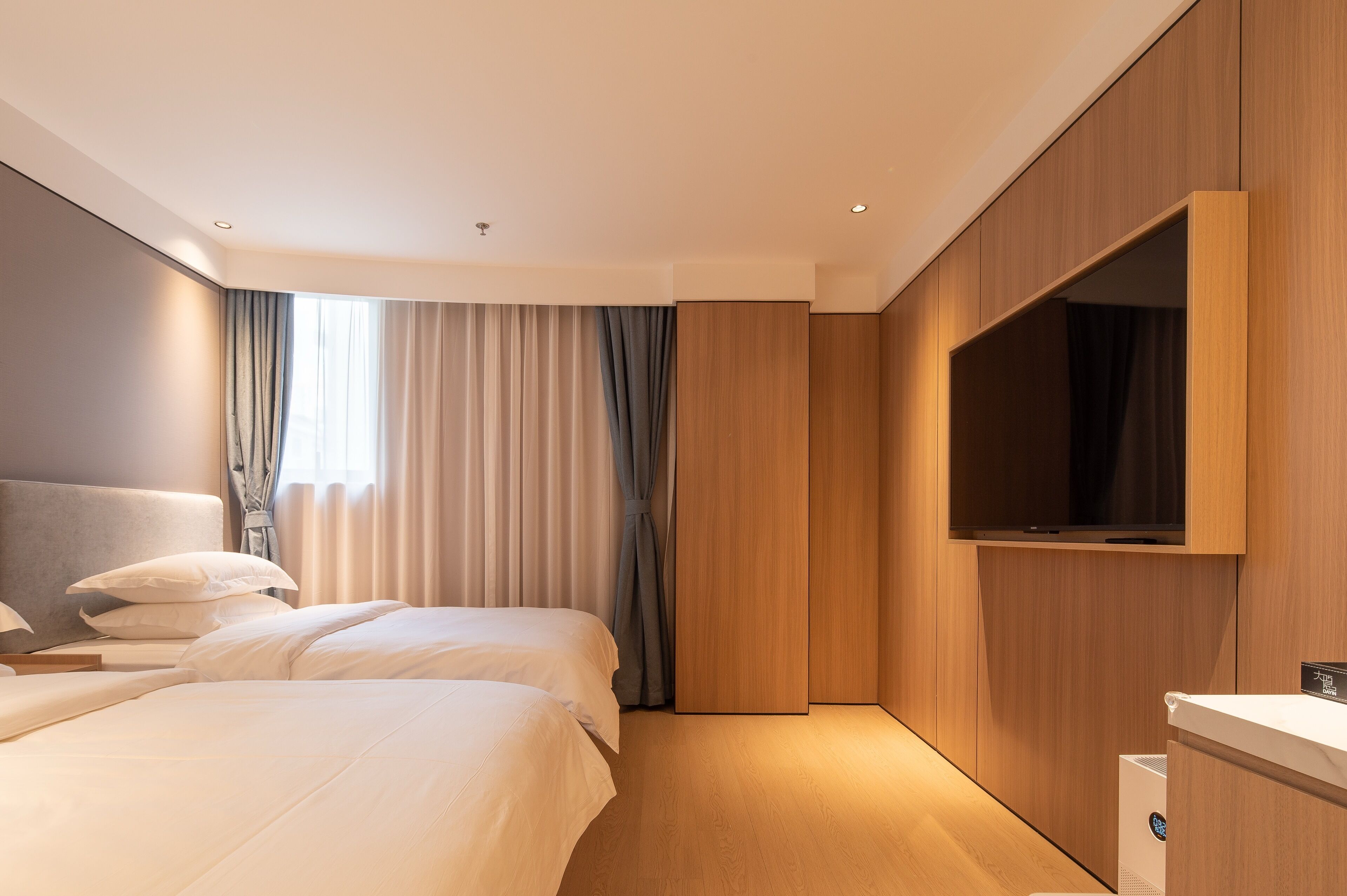 Una habitación de hotel moderna con una cama grande, un televisor de pantalla plana en la pared y un armario de madera.