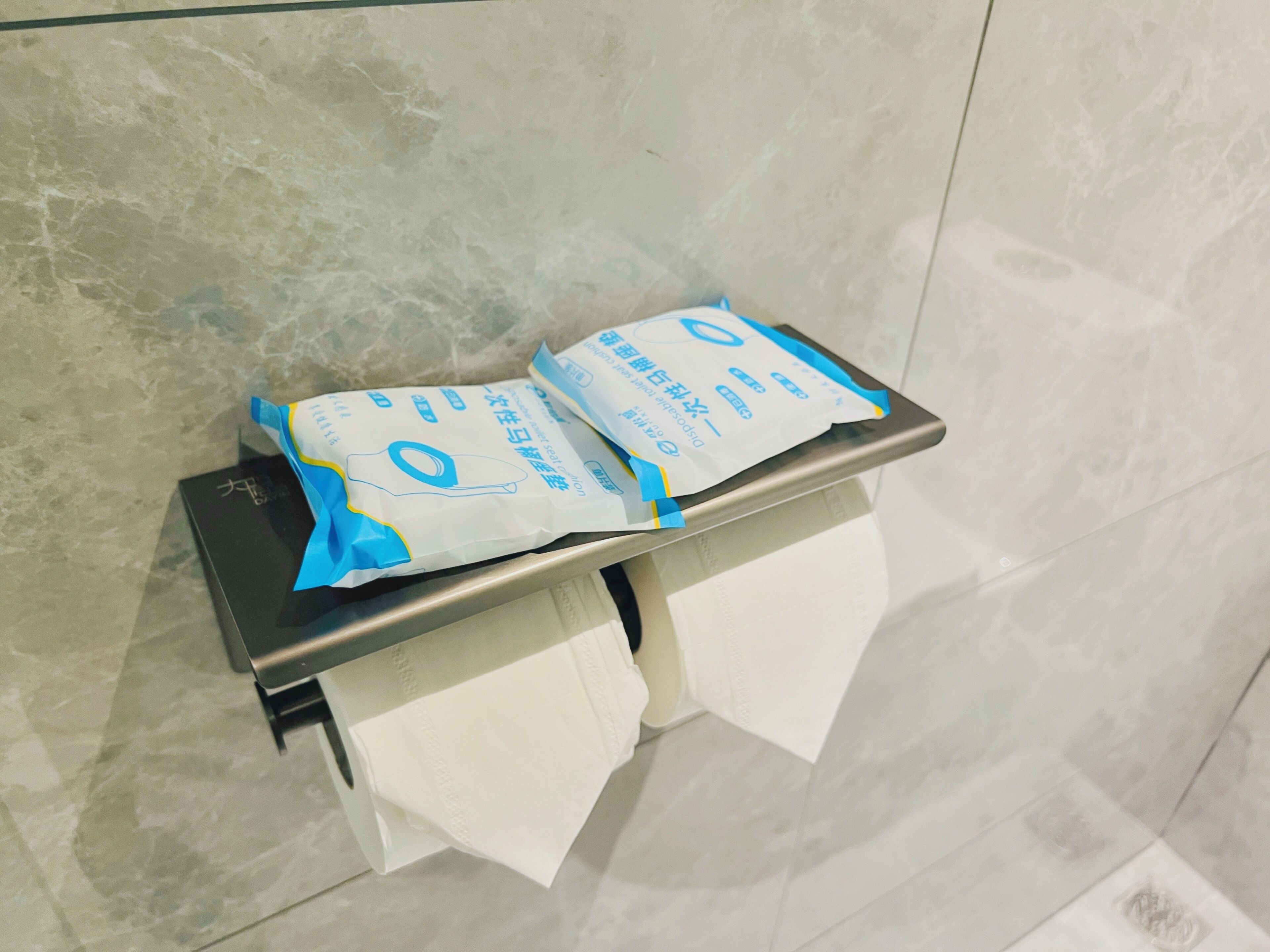 A bathroom with a toilet paper holder and two rolls of toilet paper.