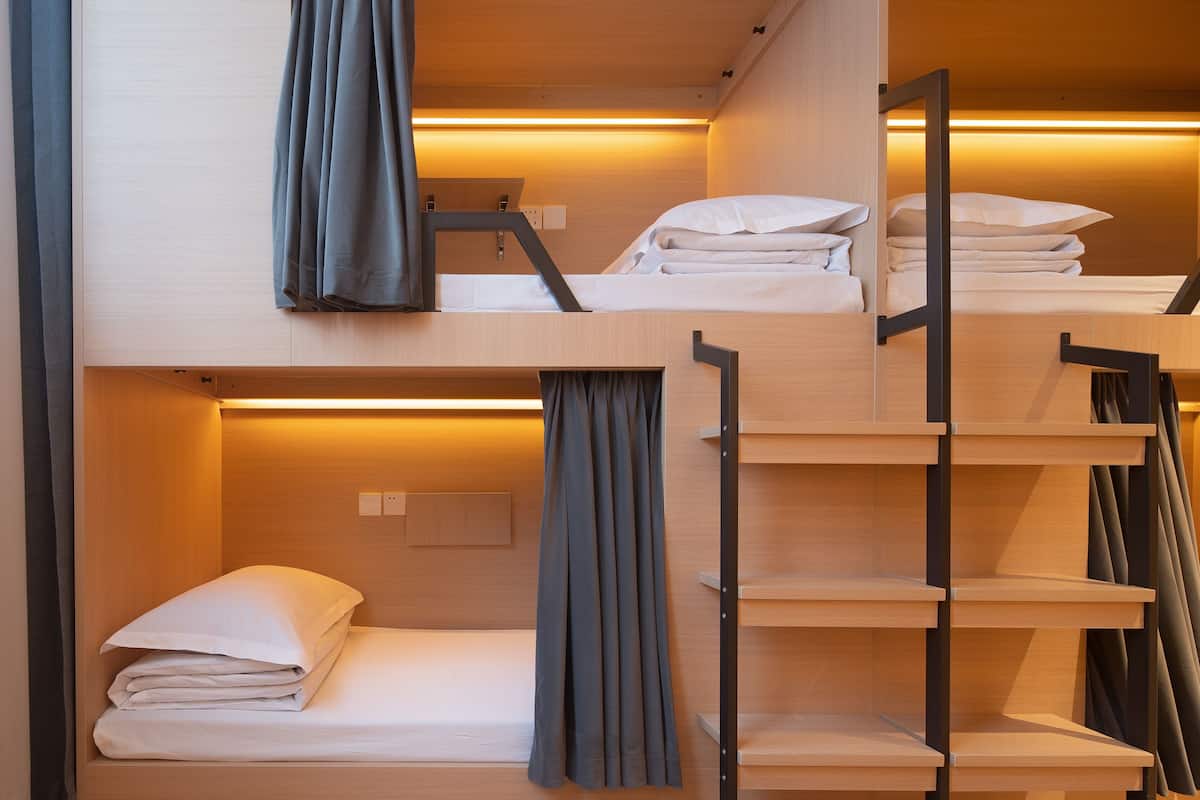 A bunk bed room with a wooden interior, a desk, and a shelf with storage compartments.