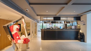 A modern reception area with a sleek black counter, a large window with a view of greenery, and a playful red bear sculpture. - Dayin Serene Garden Hotel - Shanghai Jing'an Joy City Suzhou Creek (Shanghai)