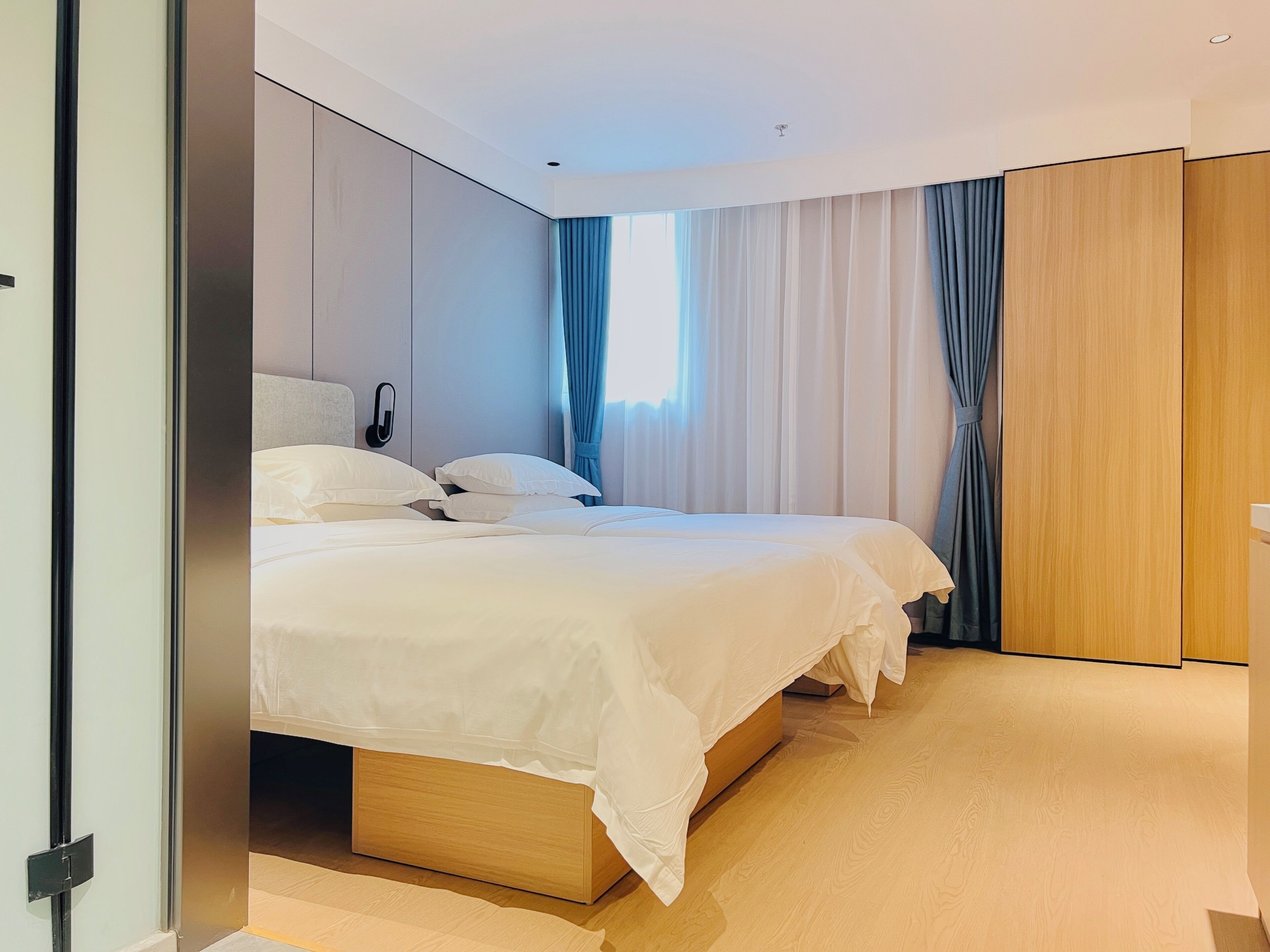 Una habitación de hotel moderna con una cama grande, un teléfono en la mesita de noche y un armario de madera.