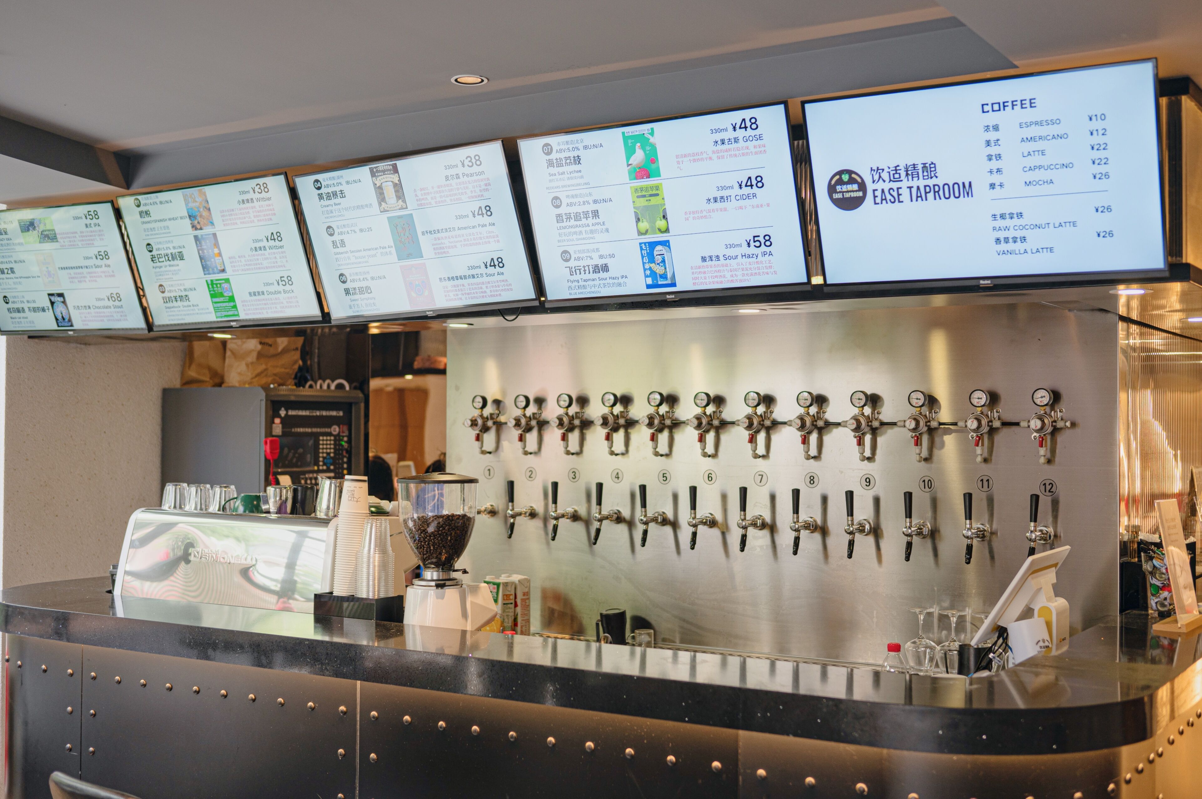 Un café proposant différentes sortes de café, avec plusieurs distributeurs et un tableau affichant les options disponibles.
