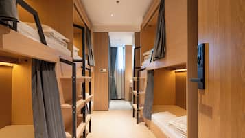 A hotel room with bunk beds, wooden walls, and a corridor leading to a bathroom.