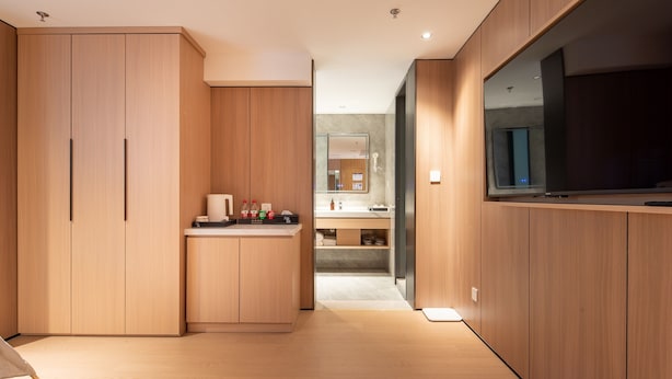 A modern kitchen with wooden cabinets, a built-in oven, and a large TV. - Dayin Serene Garden Hotel - Shanghai Jing'an Joy City Suzhou Creek (Shanghai)