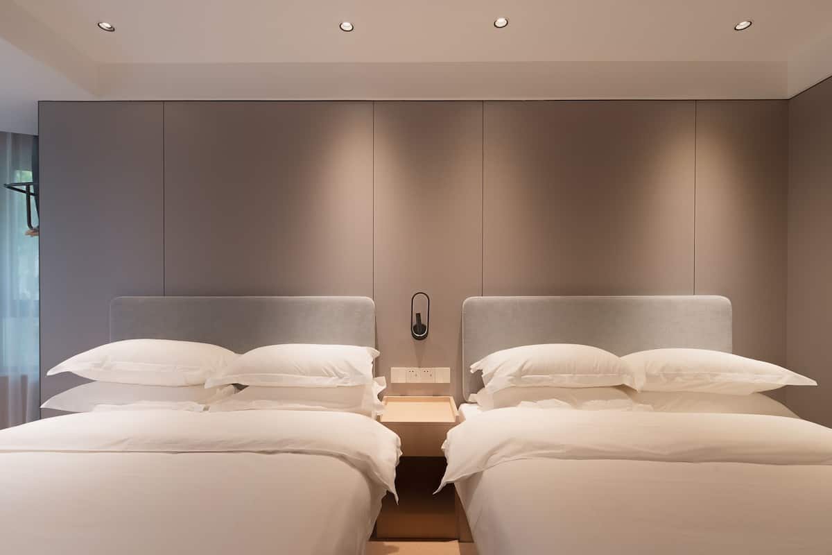 A modern hotel room with two beds, a neutral color scheme, and a built-in phone.