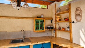 A kitchen with a wooden countertop, blue cabinets, a green-framed cabinet, and a wall-mounted shelf with decorative items. - Villa Salamander Suite - Garden & EV charger, Štanjel, Slovenia (Štanjel)