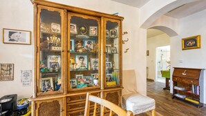 A room with a wooden cabinet filled with various items, a chair, and a bookshelf. - Villa Salamander Suite - Garden & EV charger, Štanjel, Slovenia (Štanjel)