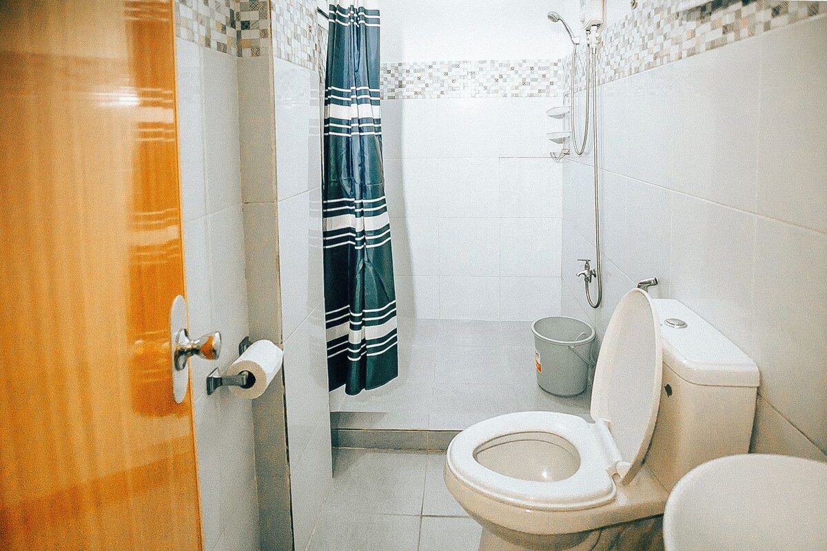 Un baño con inodoro, ducha y cortina.