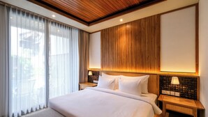 Een hotelkamer met een groot bed, een houten hoofdbord en een nachtkastje met een lamp.