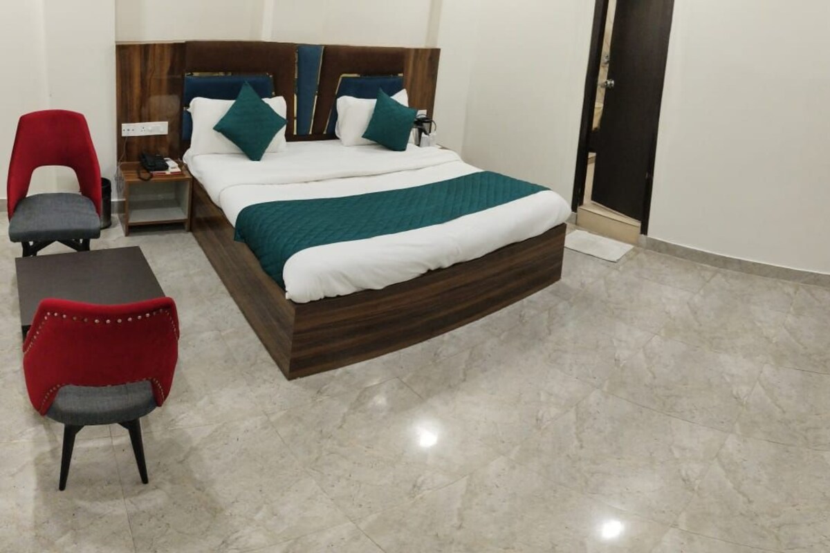 Une chambre d’hôtel avec un lit, deux chaises, une petite table et une armoire.