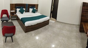 Une chambre d’hôtel avec un lit, deux chaises, une petite table et une armoire.