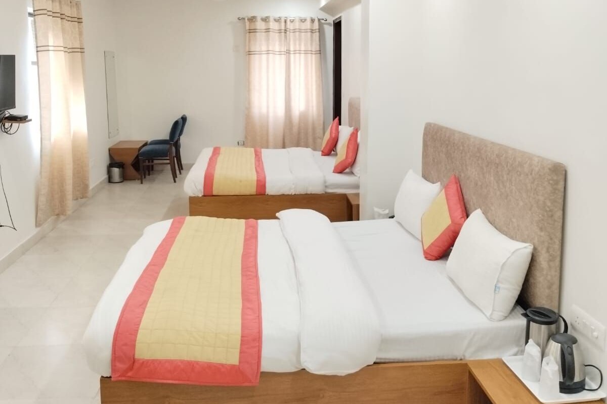 Une chambre d’hôtel avec deux lits, une table de chevet en bois, un bureau et une chaise.
