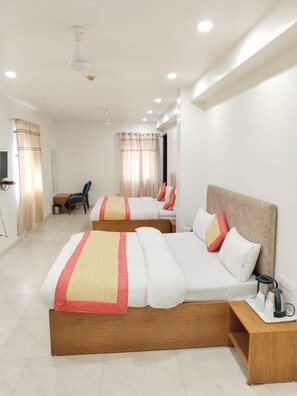 A hotel room with two beds, a wooden nightstand, a desk, and a chair. - Fortune Residency (New Delhi)