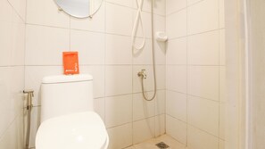 A small bathroom with a toilet, a shower, and a mirror on the wall.