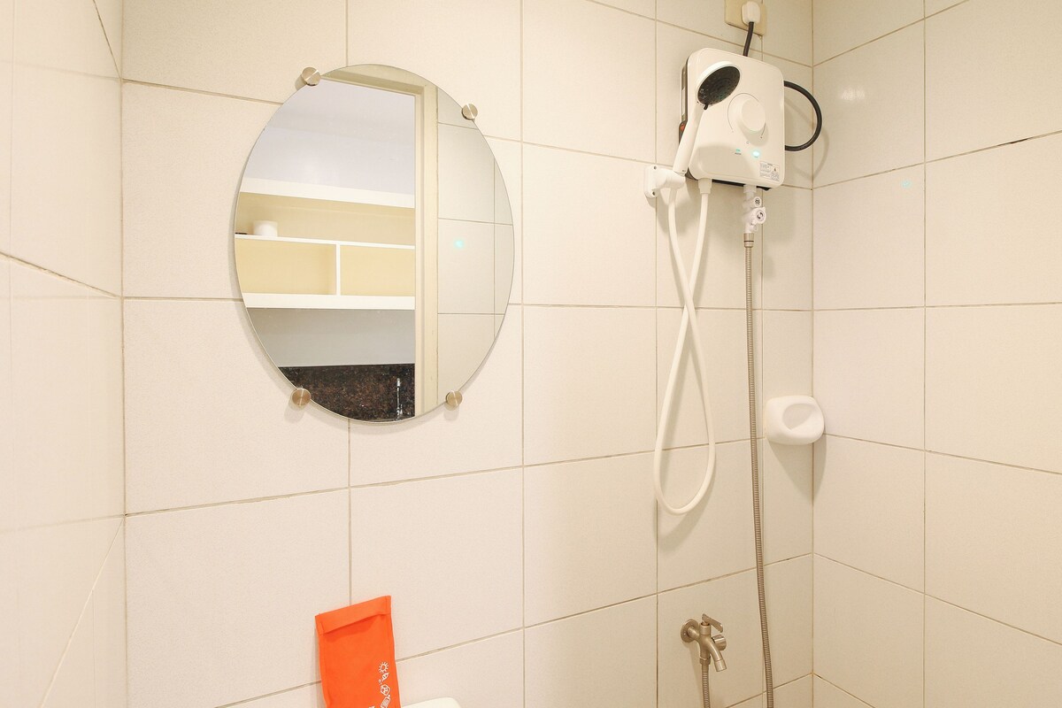 Een badkamer met een ronde spiegel, een douchekop en een toilet.