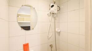 Een badkamer met een ronde spiegel, een douchekop en een toilet.