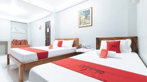 Ein Hotelzimmer mit zwei Betten, weißer Bettwäsche, roten Akzenten, einem hölzernen Kopfteil, einem Gemälde an der Wand und einer Tür.