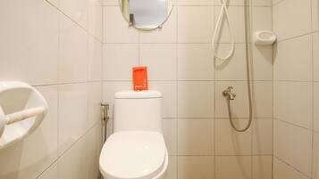 A bathroom with a toilet, a bidet, a shower, and a mirror on the wall.