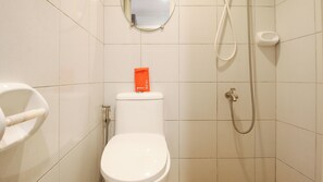 Een badkamer met toilet, bidet, douche en een spiegel aan de muur.