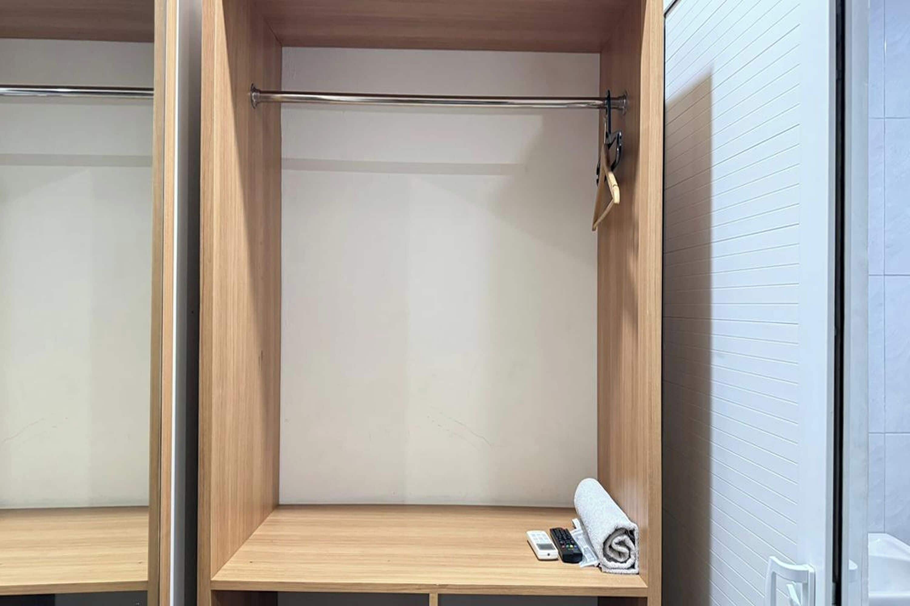 A hotel room with a wooden wardrobe, a small wooden table, and a towel on the table.
