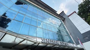 A modern building with a large glass facade and the name "SENAYAN SUITES" displayed prominently. - Senayan Suites (Jakarta)