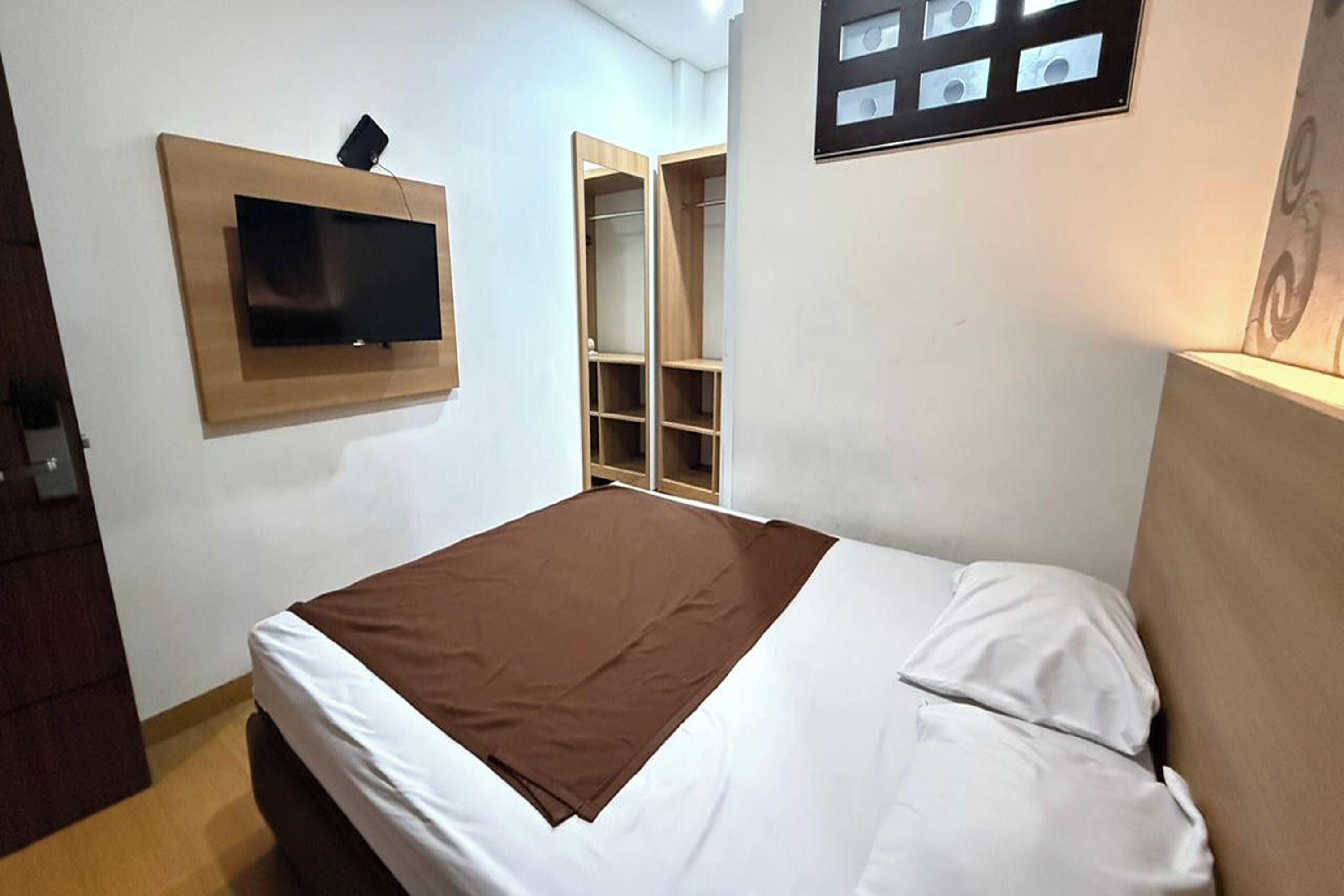 A bedroom with a bed, a mounted TV, and a wardrobe.