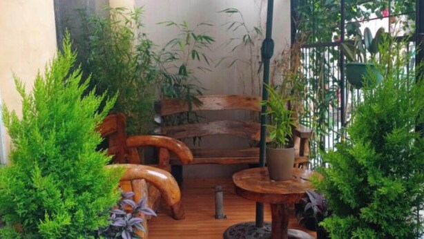 Un espace extérieur aménagé avec des meubles en bois, des plantes en pot et un grand parasol.