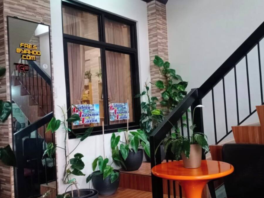 A staircase with a wooden finish, a black railing, and a small orange table with a green mat at the base.