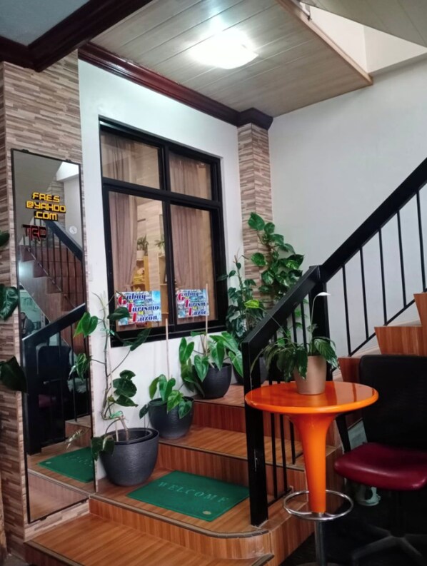 A staircase with a wooden finish, a black railing, and a small orange table with a green mat at the base.