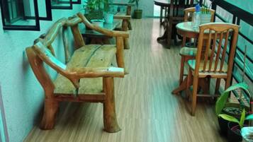A corridor with wooden benches and tables, potted plants, and a blue mat on the floor.