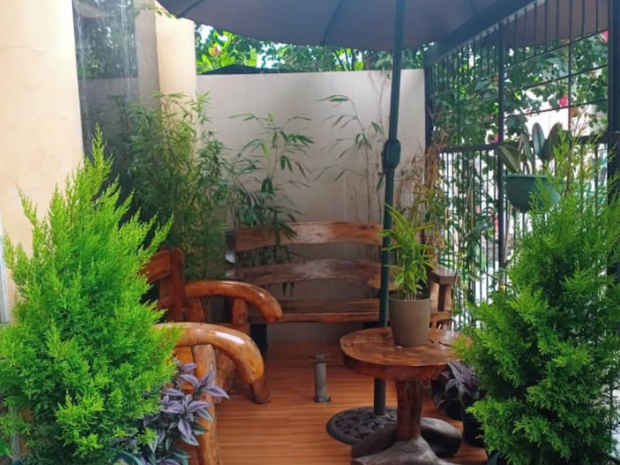 A patio area with wooden furniture, potted plants, and a large umbrella.