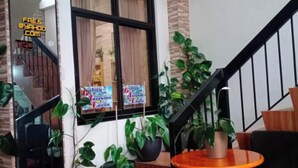 Un escalier avec une finition en bois, une rampe noire et une petite table orange surmontée d’un tapis vert.