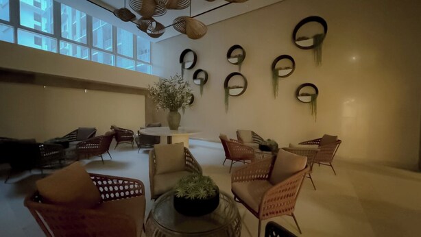 A spacious room with wicker furniture, a central round table, and multiple mirrors on the walls.