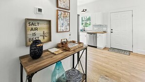 Una cocina moderna con armarios blancos, encimera de madera y ventana con vistas a árboles.