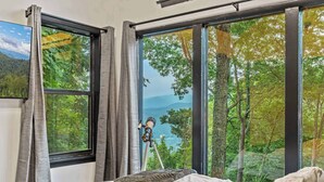 Un dormitorio con un ventanal que ofrece vistas a un bosque y montañas.