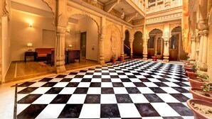 A hotel lobby with a checkered floor, ornate arches, and a seating area with a sofa and chairs. - Hotel Dev Villa (Jaisalmer)
