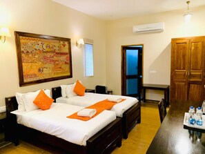 A hotel room with two beds, a large decorative wall hanging, an air conditioning unit, and a wooden wardrobe. - Hotel Dev Villa (Jaisalmer)