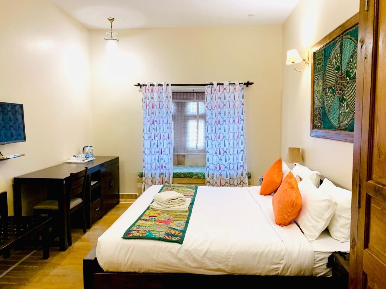 A hotel room with a bed, a desk, and a window with curtains.