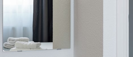 A bathroom with a wooden bench, a mirror, and towels on a windowsill.