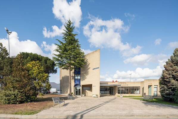 A building with a cafe and restaurant, outdoor seating, and a large tree. - Alda Puerto Seco (Burgos)