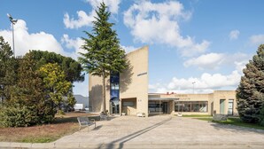 A building with a cafe and restaurant, outdoor seating, and a large tree. - Alda Puerto Seco (Burgos)