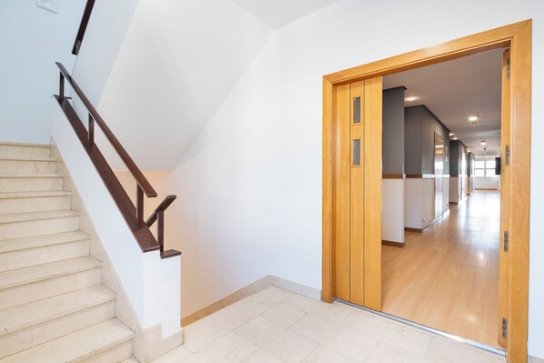 Eine Treppe mit hölzernen Geländern führt zu einem Flur mit Holztüren und Fliesenboden.