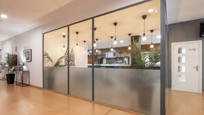A modern hotel lobby with a reception desk, a coffee bar, and a large glass partition. - Alda Puerto Seco (Burgos)