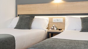 A hotel room with two beds, a nightstand, and a wall-mounted light fixture. - Alda Puerto Seco (Burgos)
